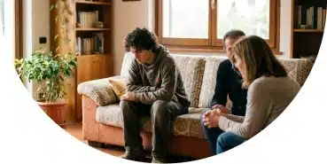 Joven sentado en el sofá mientras familiares hablan a su lado, reflejando sensación de incomprensión